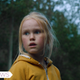 A small blonde girl wearing a yellow hoodie.